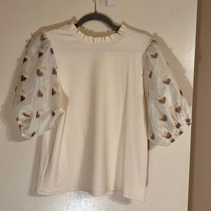 Women’s cream colored top with puff sheer sleeves.